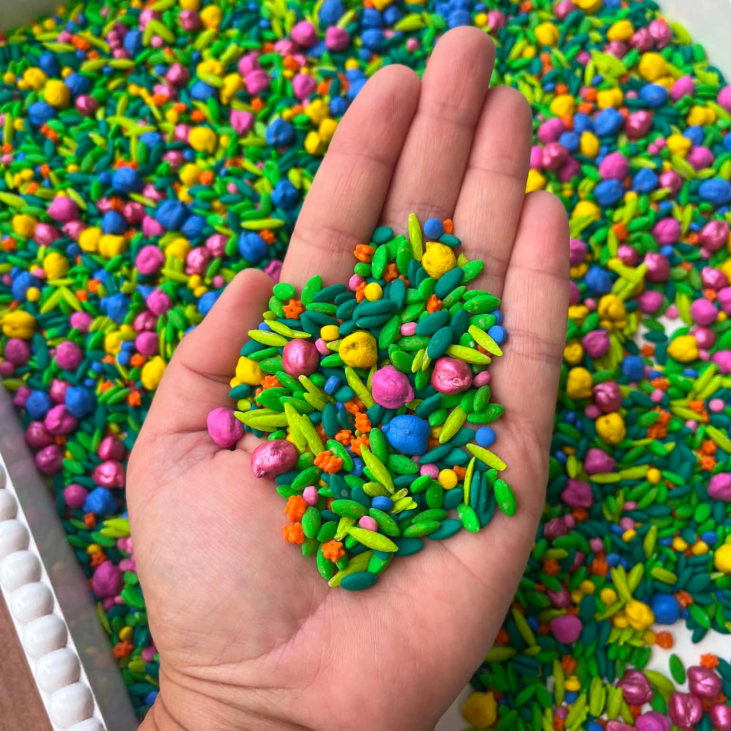 Colorful textured object held in a hand with a background of similar colorful material